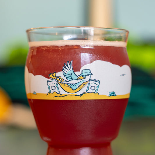 Glass of red liquid with a seagull illustration on a colorful background